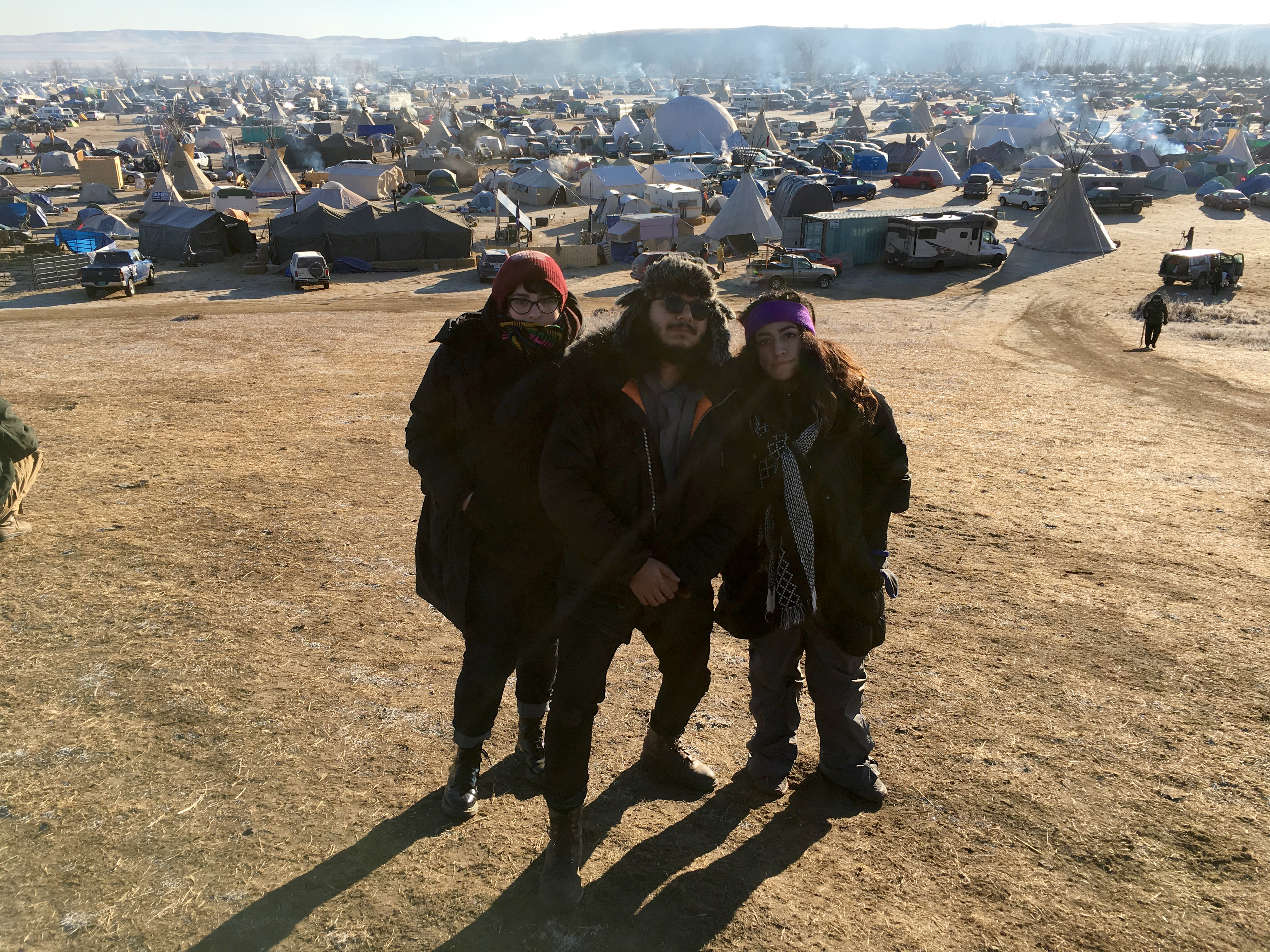 Me, Jose Alejandro Rodriguez, and Natalie Escobedo standing on top of Media Hill with view of Oceti Sakowin in the background, Photo credit: Juan Carlos Martinez