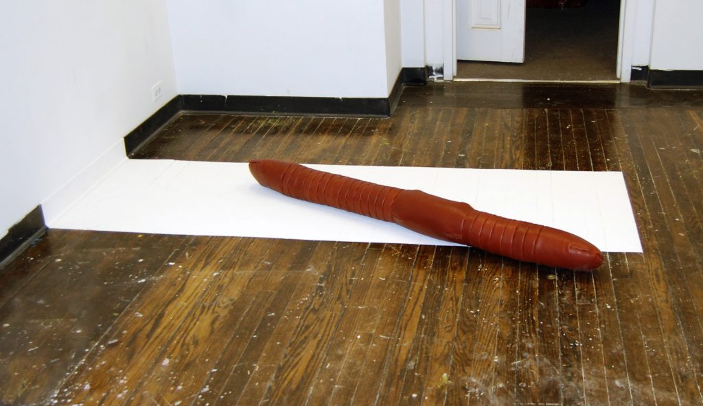 "Not a Grave," Paint element, 84"x28"; sculptural element 64" long. Leather, polyfil, thread, and paint on wooden floor. 