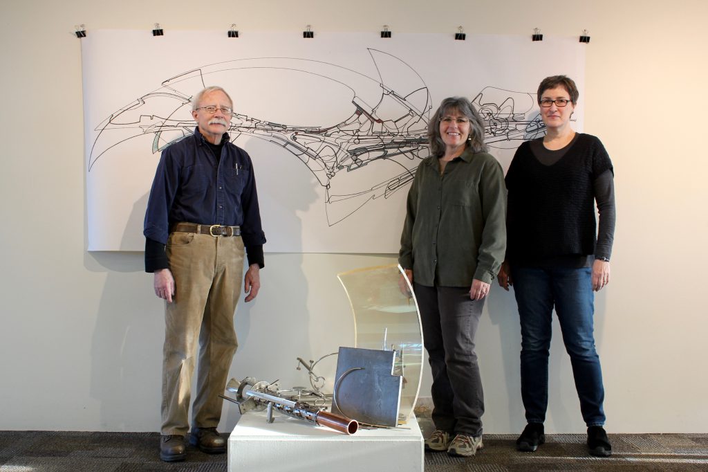 2017 Fermilab Artist-in-Residence Jim Jenkins, Georgia Schwender, and Gallery Committee Member Anne Mary Teichert stand in front of Jim's work in the gallery. Photo courtesy of Georgia Schwender.