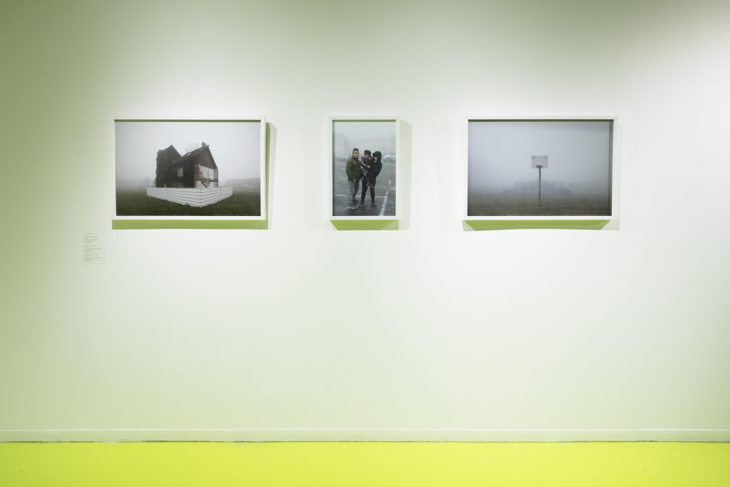 A photographic triptych from David Schalliol's Mining Basin (Hauts-de-France), showing an abandoned house shrouded in fog, a couple with their child in a parking lot, and an isolated basketball hoop. Photo courtesy of Hyde Park Art Center.