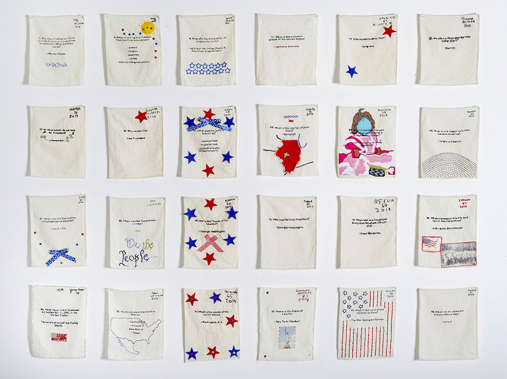“US Citizenship Test Sampler” (24 out of 120), 2013–present. Embroidered samplers made by non-citizens who live and work in the U.S. installed in a grid on the wall. Photo by Hyounsang Yoo.