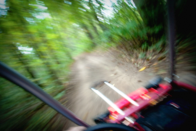 Go Cart, 2018. A blurry image vaguely depicts the first person view of a go cart in motion. A suitcase handle is jutting out into view. Image courtesy of the artist.
