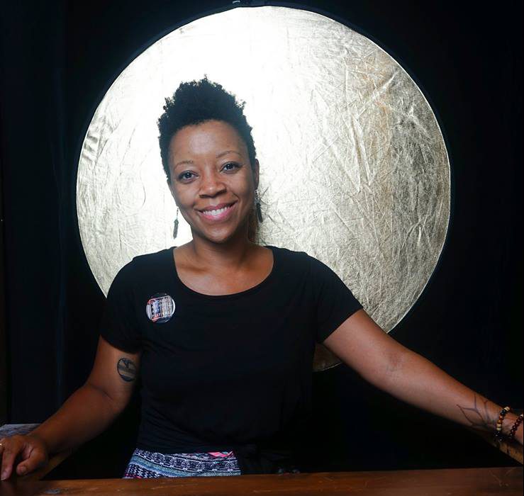 Image: Tempestt Hazel smiling while standing in front of a golden orb.