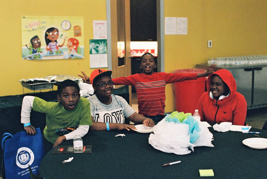 Image: Four children pose for a photo during an arts and crafts activity at BBF Family Services. BBF Family services has been in the same North Lawndale community where the RJCC convenes since 1961, and works to empower children and family in the communities. Photo by Eric K. Roberts.
