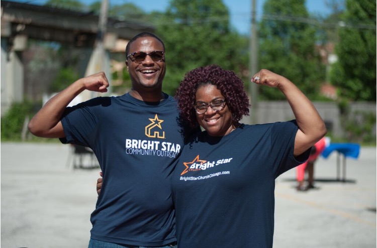 Two members of Bright Star Community Outreach pose with flexed arms