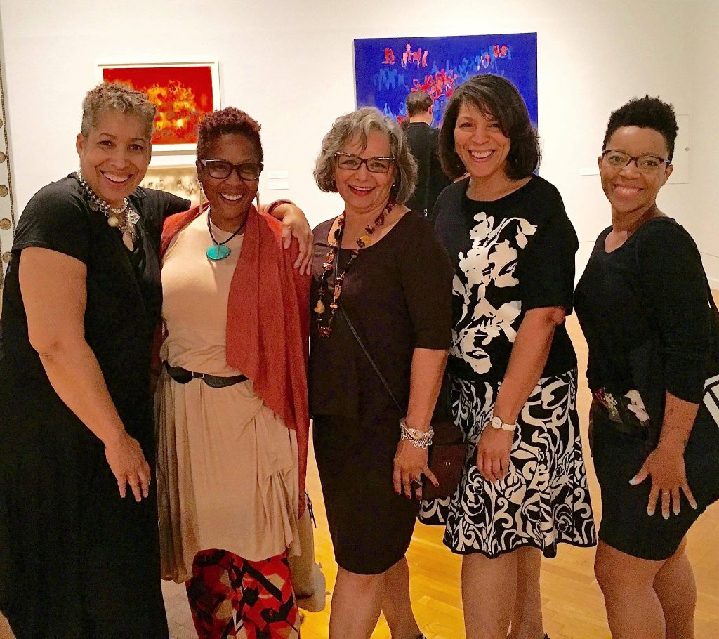 From left to right, Candace Hunter, Leslie Guy, Madeline Murphy Rabb, Michelle Bibbs, and myself at the opening reception of Norman Lewis' exhibition at the Chicago Cultural Center in September 2016. The image shows five women from the knee up, standing side by side with two small paintings on the wall in the background. Photo courtesy of Candace Hunter.