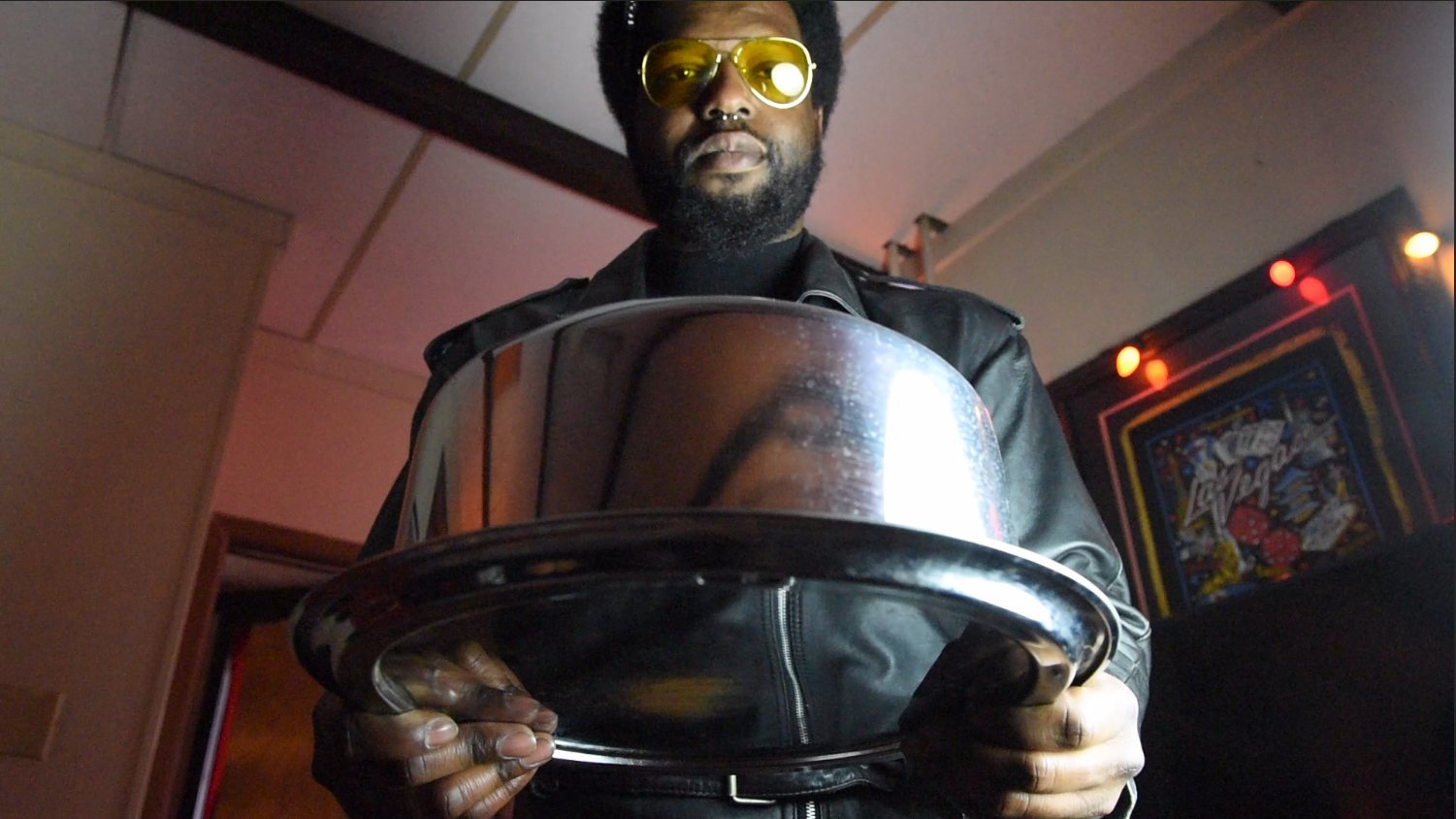 Image: Film still from "Thirst Trap" featuring actor Blackson leaning forward in preparation to serve his queen cake from a stainless steel cake carrier. Photo courtesy of Heather Raquel Phillips.