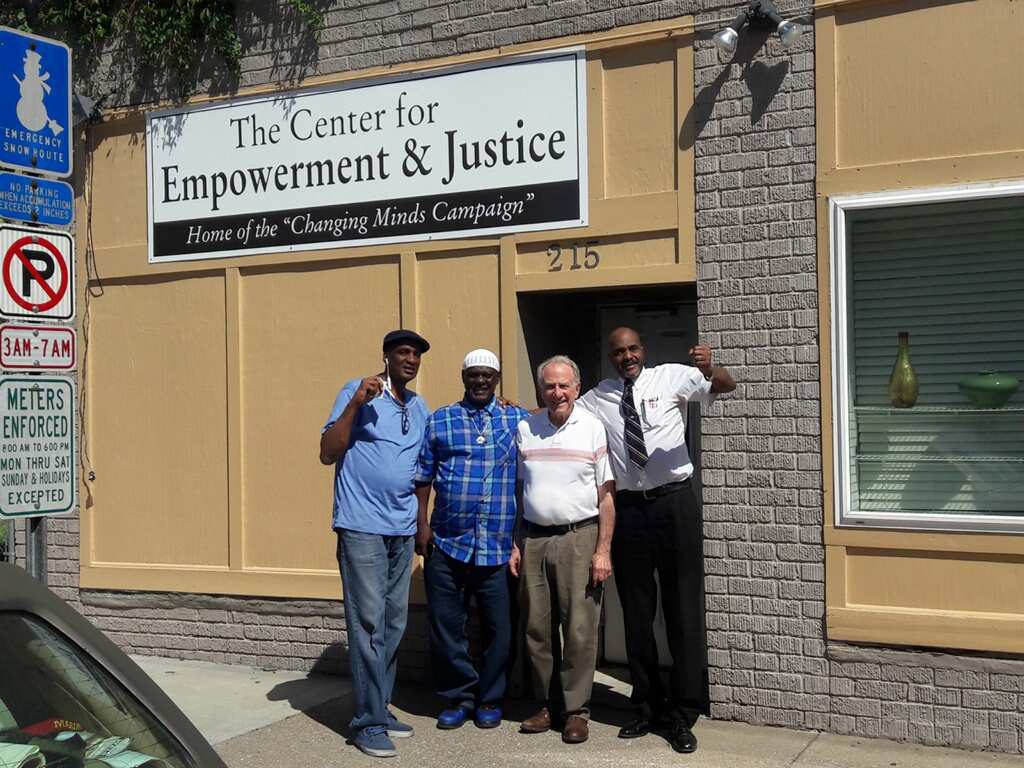 Image: Danny Franklin and three other men stand on the sidewalk outside “The Center for Empowerment & Justice: Home of the ‘Changing Minds Campaign.’” Photo courtesy of Michael Fischer. 
