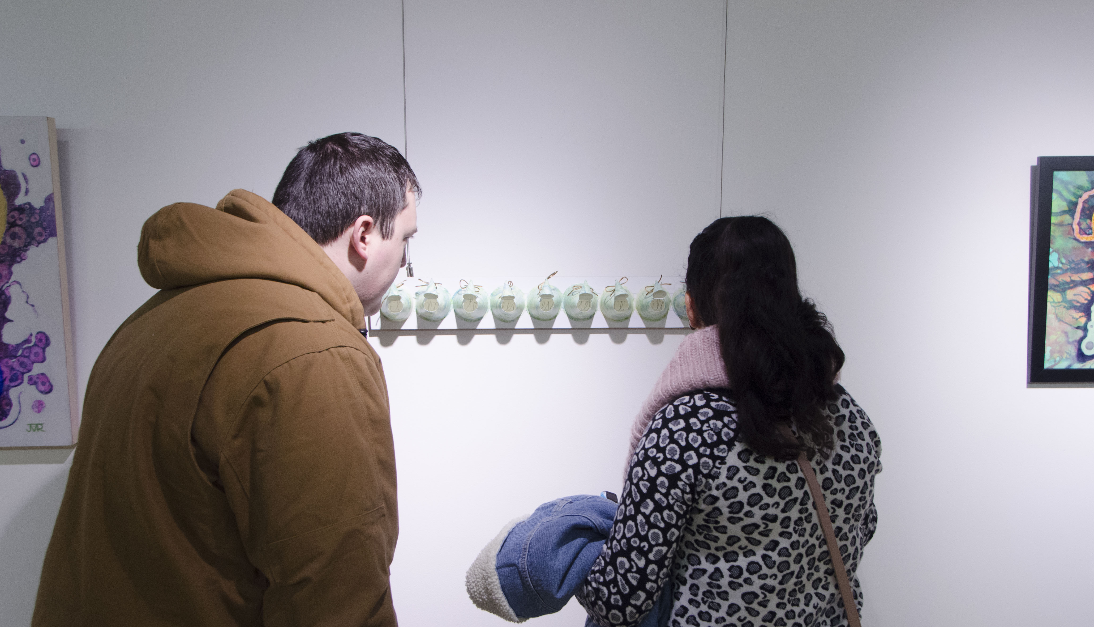 Two guests closely examine "Seem" a piece by EAC member Barbie Perry