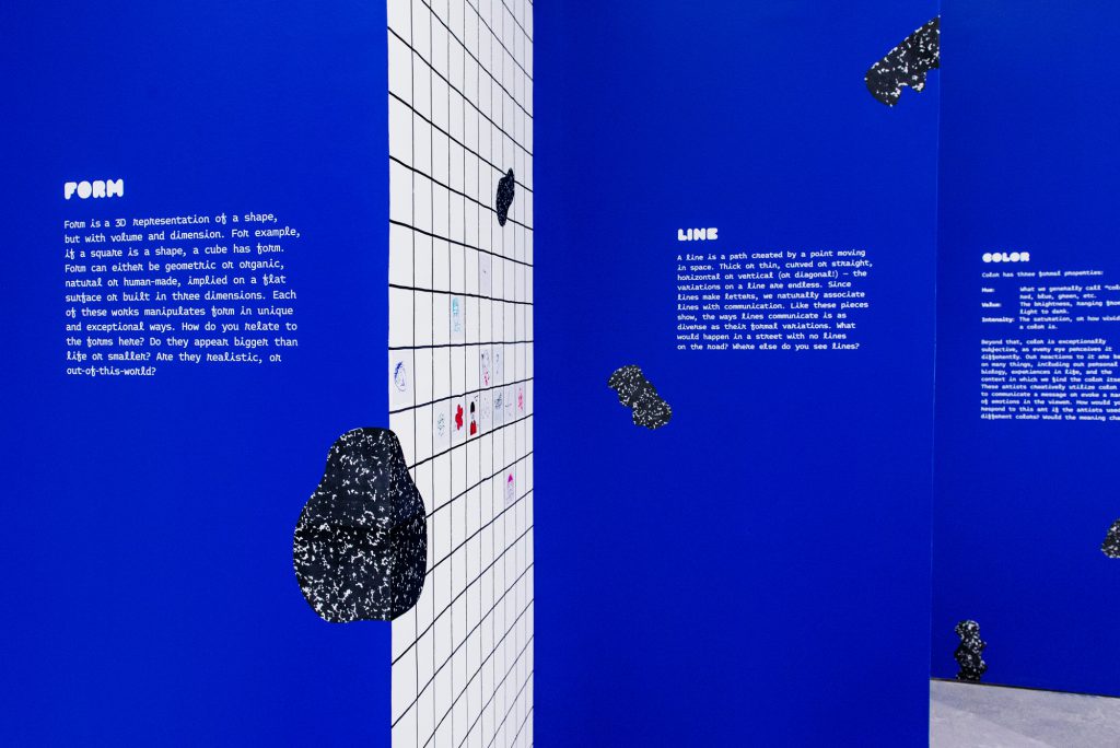 Image: Detail of the exhibition's constructed blue walls. The wall in the foreground displays the definition of "Form," while the walls in the background display the definitions of "Line" and "Color." Photo by Ryan Edmund.