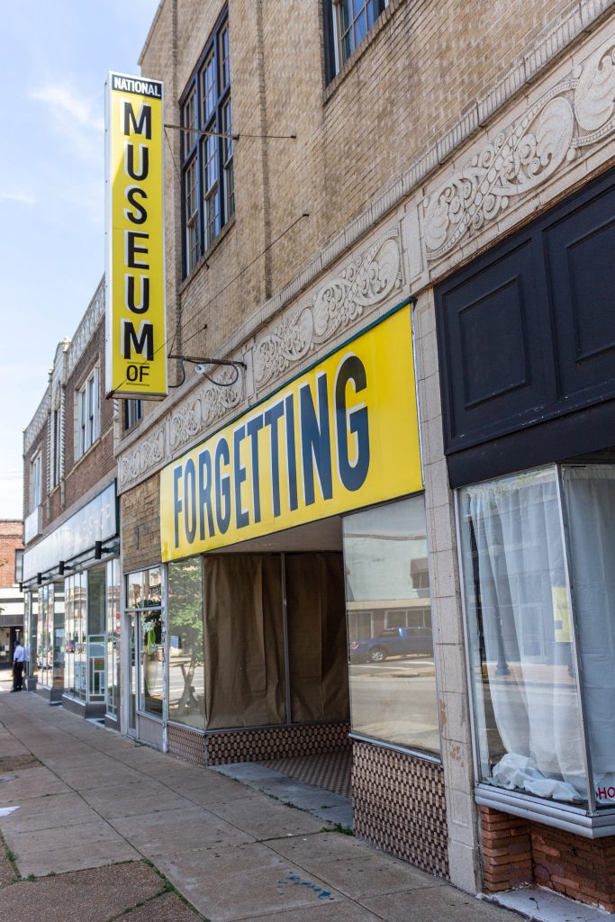 Image: Joseph del Pesco and Jon Rubin, Monuments, Ruins and Forgetting; 2019. Installation with changing signpainting. A vacant storefront has two large yellow sign that together reads "The National Museum of Forgetting." Photo by Shabez Jamal. 