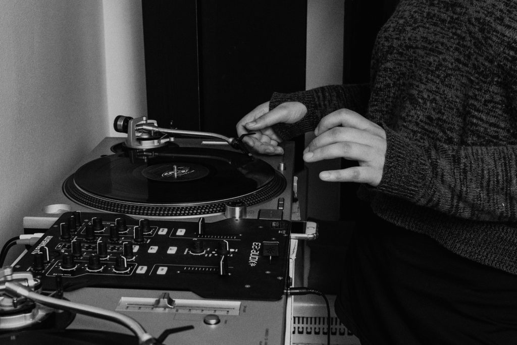 Image: Ariel places the needle on a record in a black-and-white photo. Photo by Ryan Edmund.