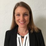 Image: A headshot of the author, Astrid Kaemmerling. She is smiling looking straight out at the viewer. She is wearing a black jacket and a white shirt.