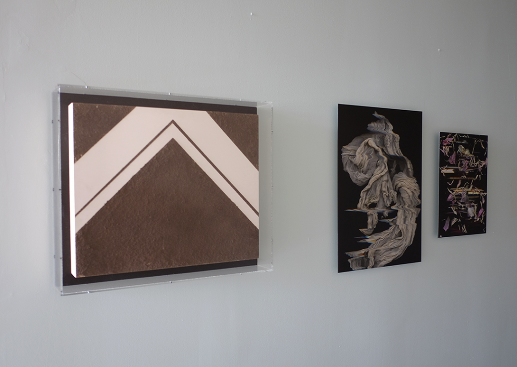 Image: Three images hung on a white wall. Left, Kat Larson's Untitled (Dirt Painting) contained by a glass pane. To the right are Kiam Marcelo Jiam's Sheath and Pink Panagnip. Image courtesy of FLXST Contemporary.