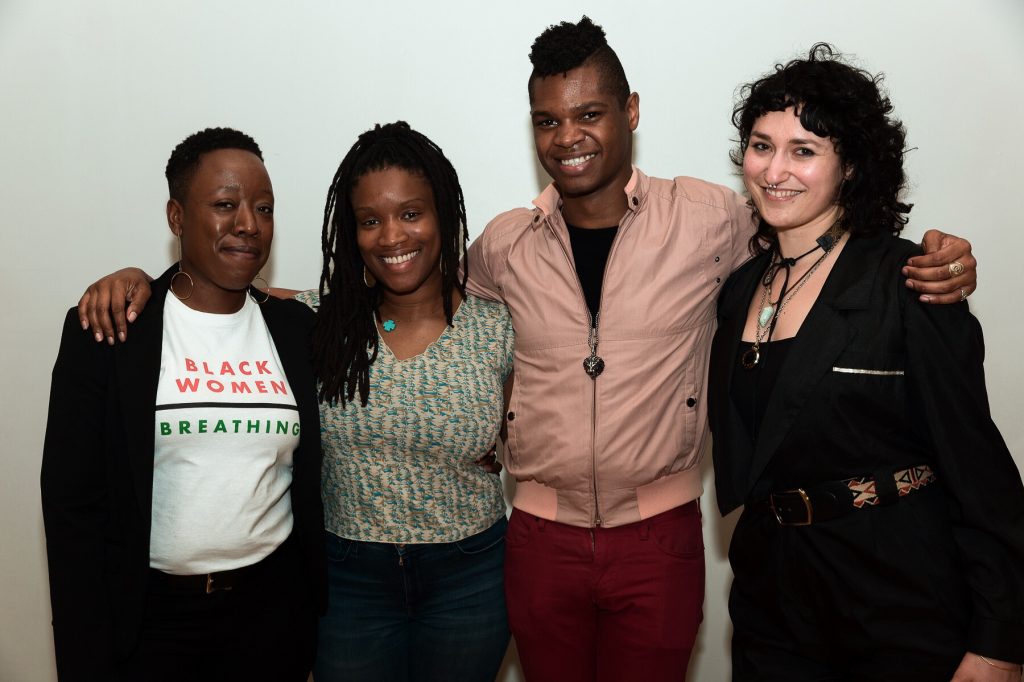 Image: Regina Martinez with Threewalls colleagues. Dr. Jeffreen M. Hayes, Lauren Williams, Omar Dyette, and Martinez (from left to right) stand with arms around each other, posing for the camera. Hayes wears a black jacket open over a white t-shirt that reads “Black Women | Breathing”; Williams wears a green, brown, and blue patterned shirt; Dyette wears a mauvish tan jacket zipped over a black shirt; and Martinez wears a black jacket clasped closed with a black, red, and tan patterned belt. Photo by Milo Bosh. Courtesy of Threewalls.