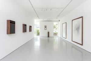 Installation View of Nate Young Exhibition. Six text and image artworks on white walls with one sculpture made of wood and bone.