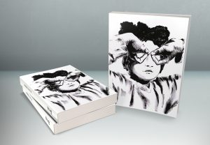 This is a photograph of three copies of the book “Brea,” against a light background. Two lie flat in the left side of the frame, front cover and spine visible, and the third is upright, with only the front cover showing. The front cover image is an ink illustration of a young boy in close-up, straight-on, showing his face, chest, and parts of his arms. He wears a long-sleeved shirt and his hands are flipped upside-down over his eyes to form goggles, of sorts, with each thumb and forefinger. Courtesy of the artist.