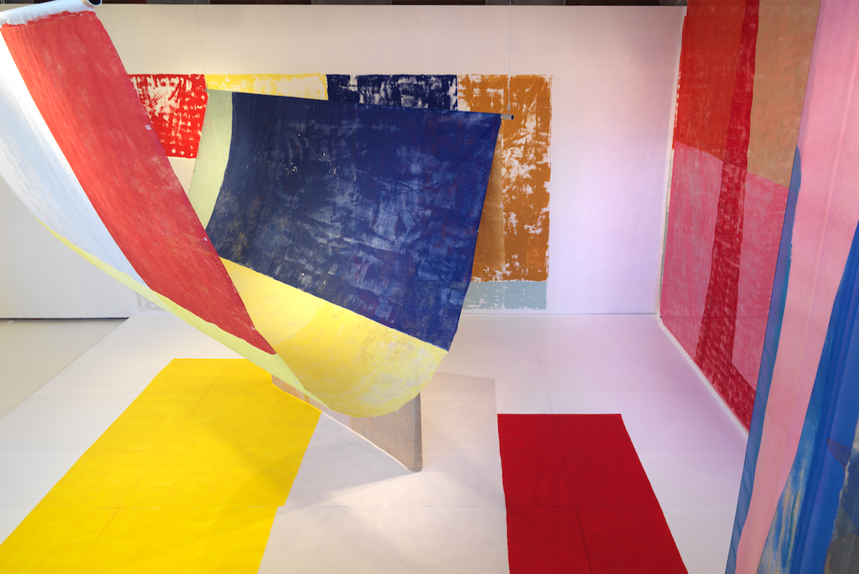 This image shows Anna Kunz’s exhibition Color Cast at the Hyde Park Art Center, a series of curtain-like textiles and wall paintings turn the gallery into an immersive experience of color, light, and physical sensation. Anna Kunz Color Cast installation view, 2018, at Hyde Park Art Center, Chicago. Photo courtesy of Hyde Park Art Center, Chicago.