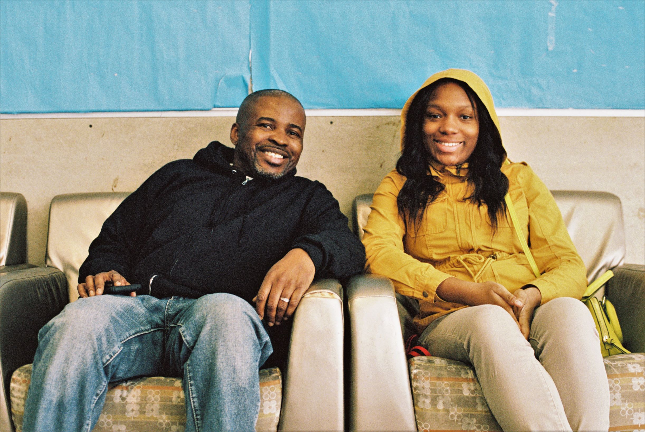 Image: George Wilson and a young woman, a client at BBF Family Services, smiling into camera and sitting on a beige couch at BBF. Photo by Eric K. Roberts.