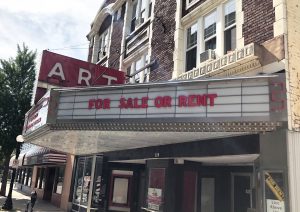 Featured Image: The marquee of The Art Theater in Champaign, Illinois reads “For Sale or Rent.” The Art Theater’s sign is red and retro. The brick building is located on a downtown street, with residential apartments above the theater. Photo by Jessica Hammie.