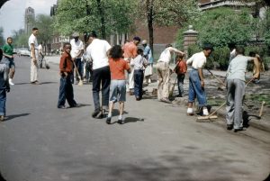 University of Chicago Photographic Archive, [apf2-09786], Special Collections Research Center, University of Chicago Library. Photo shows about a dozen adults and children outdoors in Chicago's Hyde Park-Kenwood neighborhood, many of them sweeping the streets with brooms.