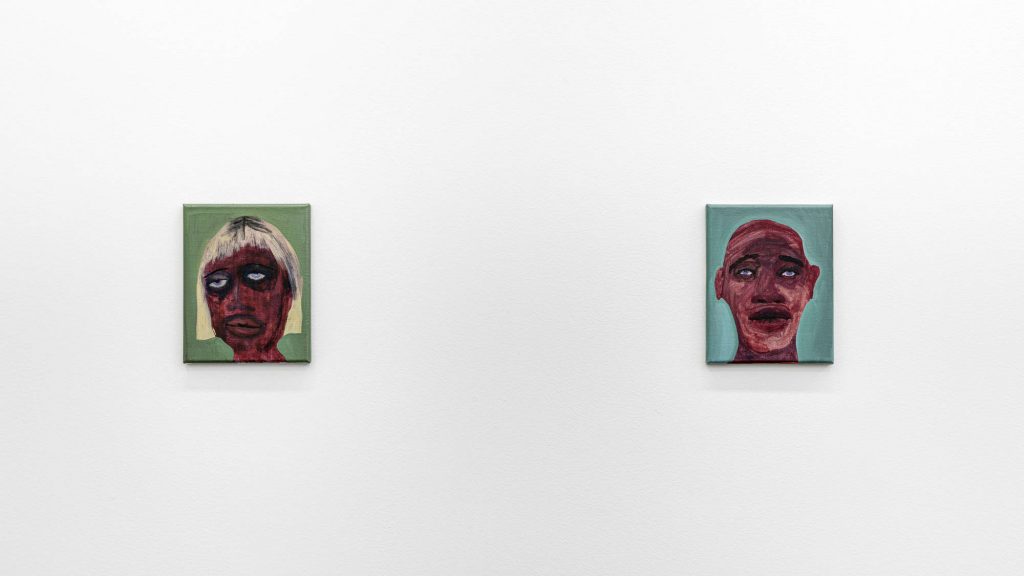 Image: Installation view of the exhibition We Laugh Loud So The Spirits Can Hear, 2020, featuring the work of February James from. Two small scale oil-painted portraits hang on a wall. The dark-skinned faces are depicted in a washy style, which creates a stark contrast to the flat backgrounds of sage green (left) and turquoise (right). Image courtesy of the artist and Monique Meloche Gallery. 