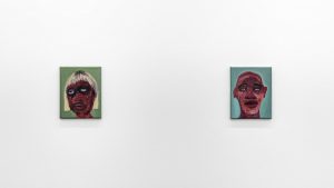Image: Work by February James. We Laugh Loud So The Spirits Can Hear, 2020. Installation view. Two small scale oil-painted portraits hang on a wall. The dark-skinned faces are depicted in a washy style, which creates a stark contrast to the flat backgrounds of sage green (left) and turquoise (right). Image courtesy of the artist and Monique Meloche Gallery.