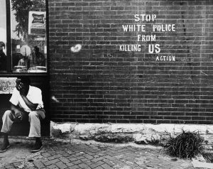 A black and white photograph titled Stop White People From Killing Us - St. Louis, MO, c. 1966-67 by Darryl Cowherd