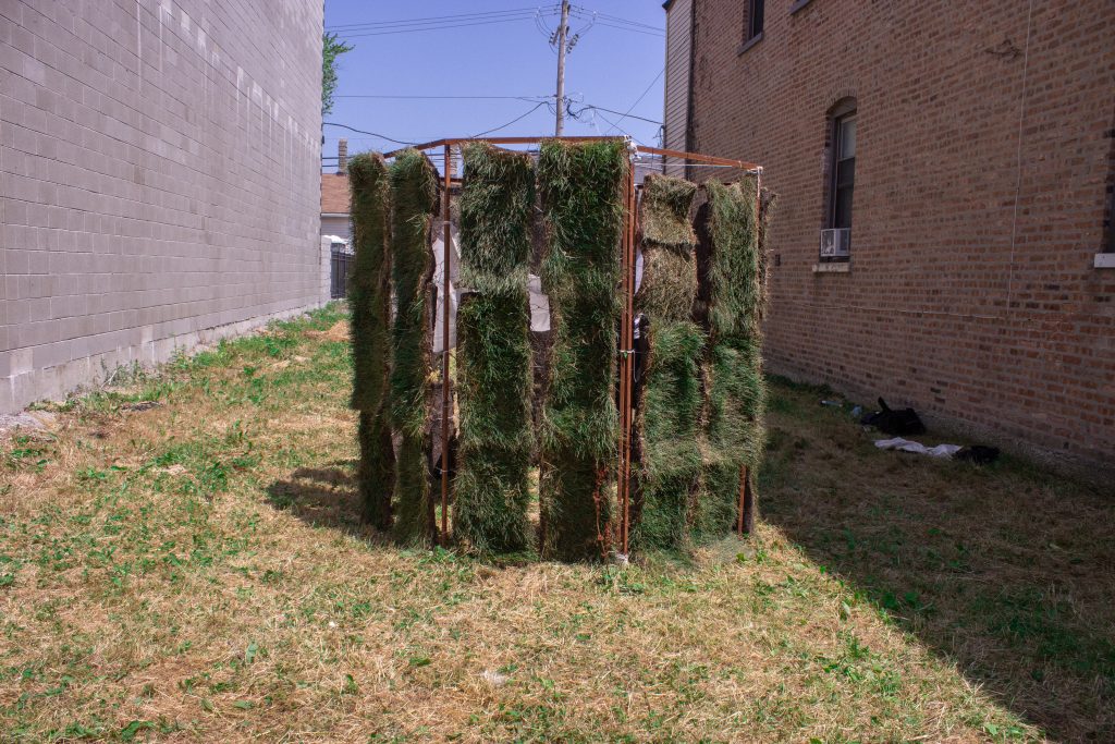 Image: "Molt" by Graham Livingston, on view October 21 - November 1, 2020 in Garfield Park. An octagon metal frame with strips of dirt and grass as the walls of the structure. Photo by Marina Resende Santos.