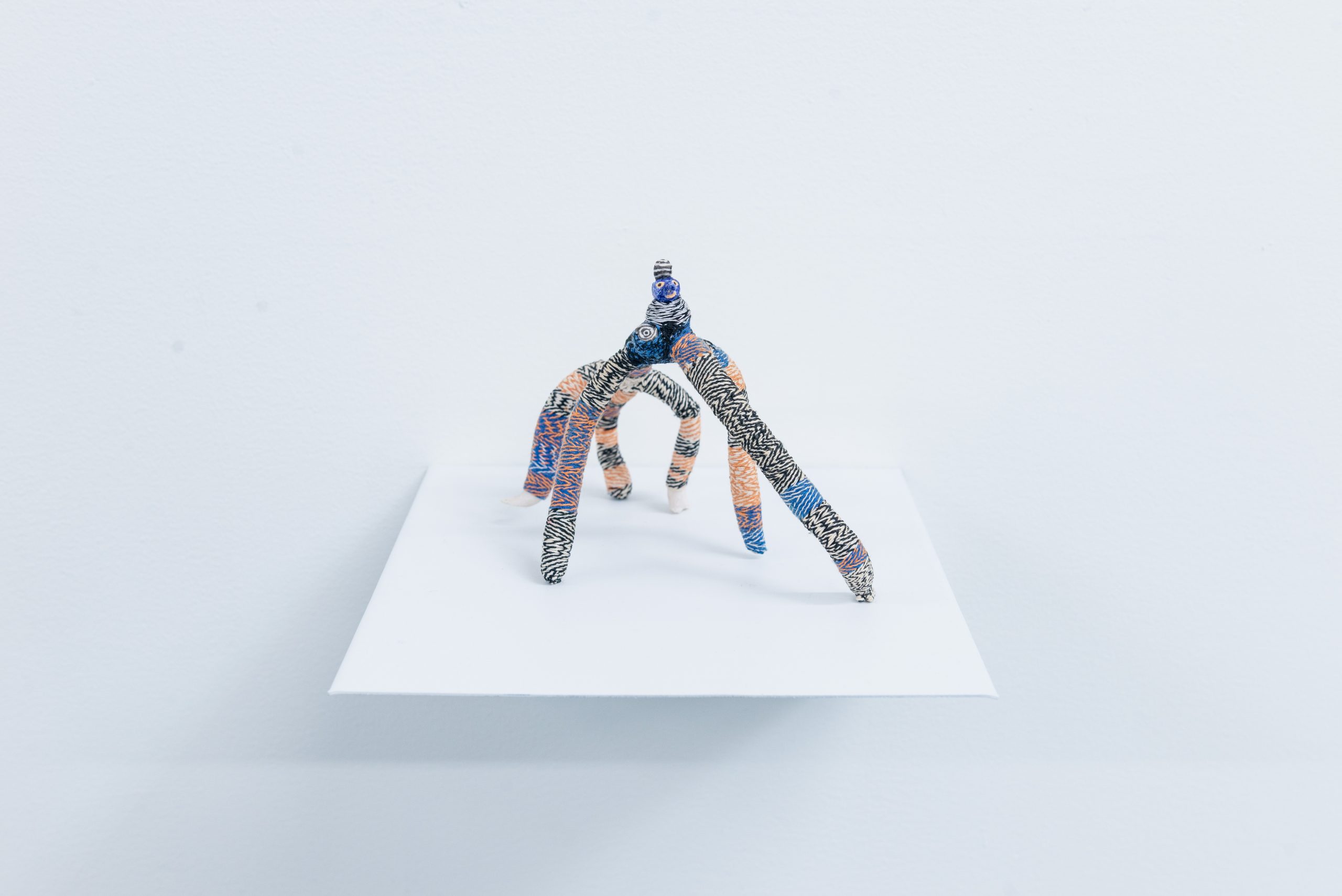 The Creep by Em Kettner; a six-legged, woven, porcelain figure looks straight ahead