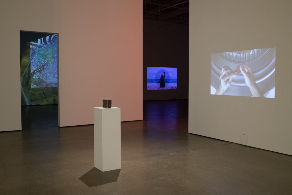 Image: Installation view of November at Beeler Gallery. The video projection on the right wall and sculpture: The Work by Lexie Smith; Drapetomania by Bobby T Luck is in the room to the left; and the video piece on the back wall: a reflection of the sky (waterway) by Adee Roberson. Image courtesy of the gallery. Photo by Ty Wright.