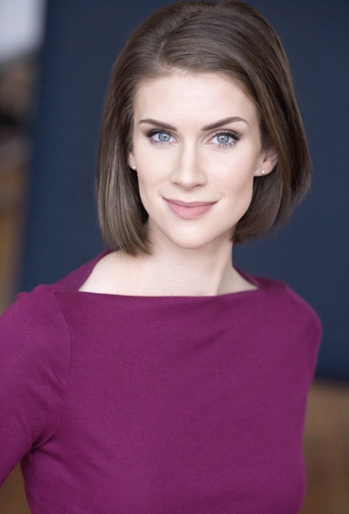 Image: A headshot of Brit Cooper Robinson. She is wearing a maroon shirt and looking straight at the viewer.