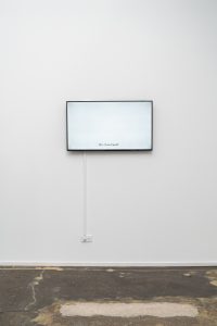 Jazmine Harris, Re-membering (lobby conversations), 2020, HD single-channel video. Screen mounted on exhibition wall is white, with the text, "Do I Live Here?" Photo courtesy of the artist and curator.