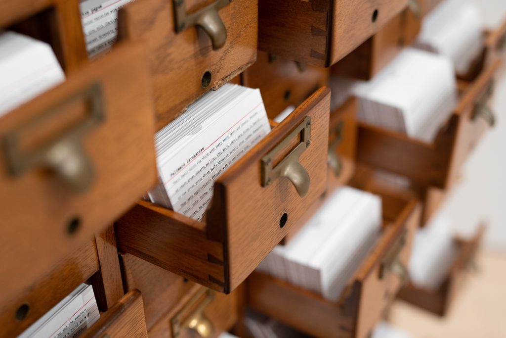 Image: A close up view of Encyclopedia by Johannes Heldén and Hokan Jonson as part of Seeds of Resistance at the Eli and Edythe Broad Art Museum at Michigan State University, 2021. Several wooden drawers are open and hold notecards. This piece is titled Photo: Eat Pomegranate Photography. Image courtesy of the museum.