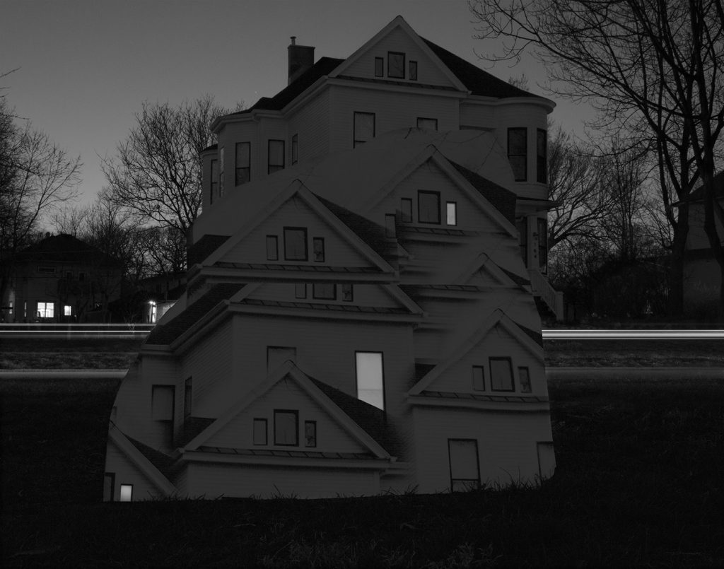 Image: Kelly Kristin Jones, "Untitled (From pillar to post)," 2021. Archival pigment print, 16in x 20 in. Edition of 3. A black and white photograph of a white house with trees and other houses behind it. Sections of the house have been duplicated and cloned in a way that is layered and overlapped. Image courtesy of the artist.