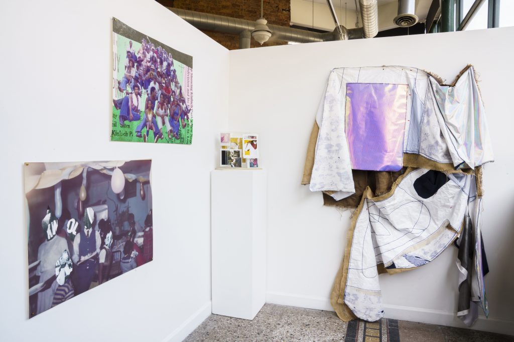 Image: A view of "Dreamscapes: Imaginings of a Black Pastoral" at Roots and Culture. On the right side is a large textile piece, and on the left are three photographic pieces on display. Photo by Colectivo Multipolar.