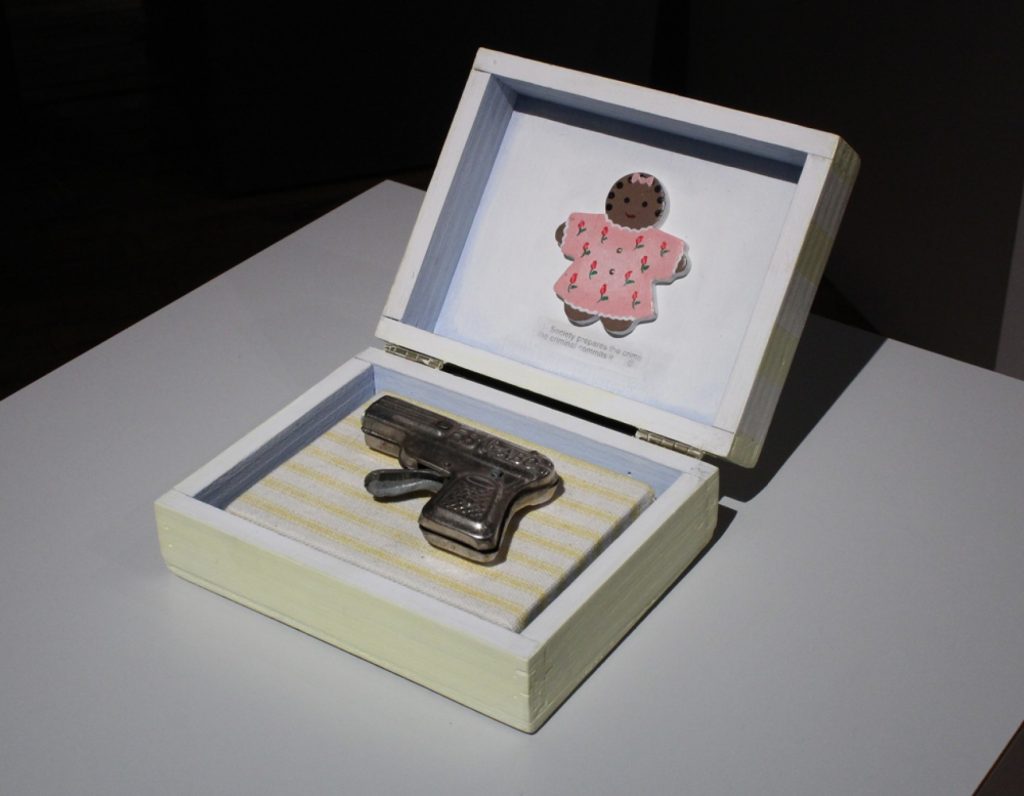 Image: Renée Stout, "Baby’s First Gun," 1998. Mixed media and toy gun. An open box displays a cap gun and a gingerbread girl cutout with text that reads: “Society prepares the crime, the criminal commits it.” Courtesy of Belger Arts Center, Kansas City, MO.