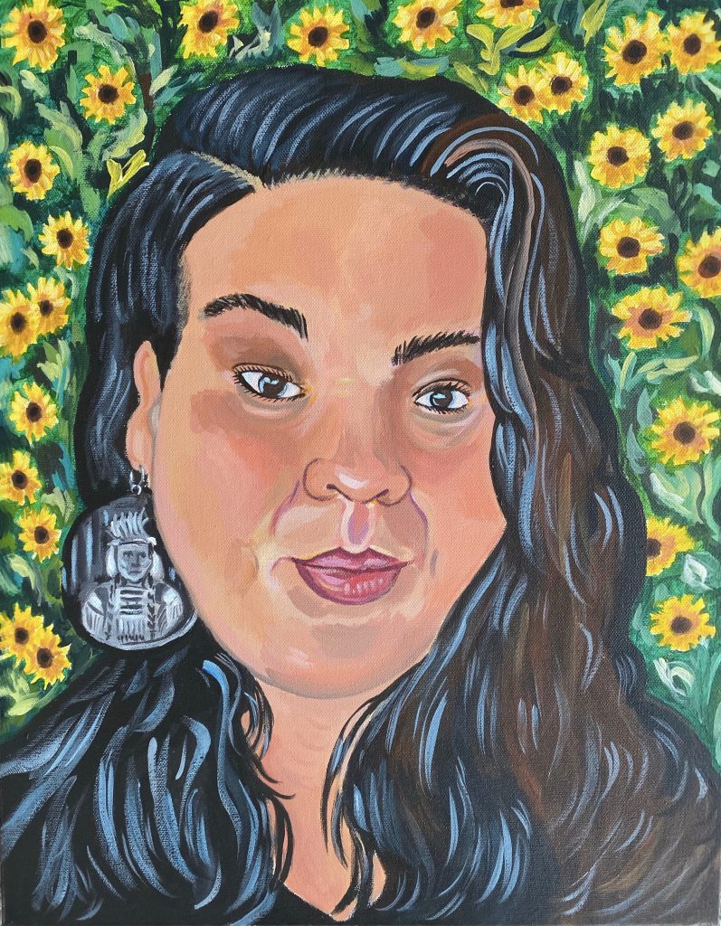 Image: A portrait of Fawn Pochel by Irina Zadov. Image depicts a woman from the shoulders up draped by long black hair. Her lips are slightly pursed and is wearing a grey earring with a figure engraved on it. Behind her is a field of sunflowers. Image courtesy of the artist.