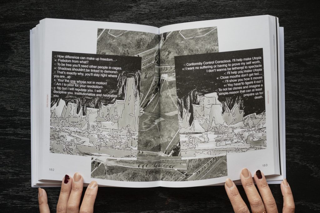 Image: The book Fleeting Monuments for the Wall of Respect is open to pages 182 and183, showing a compilation of text and images by artists solYchaski. The foreground images appear to be coded and pixelated images of different geographies. The background image is an abstracted above view of streets, trees, and open, flat landscape. Photo by Ryan Edmund Thiel.
