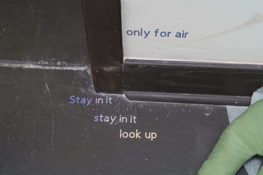 Image: Installation view of UTENSIL at Comfort Station. Vinyl text on the wall and floor say "only for air" and "Stay in it / stay in it / look up". Image courtesy of Annas.