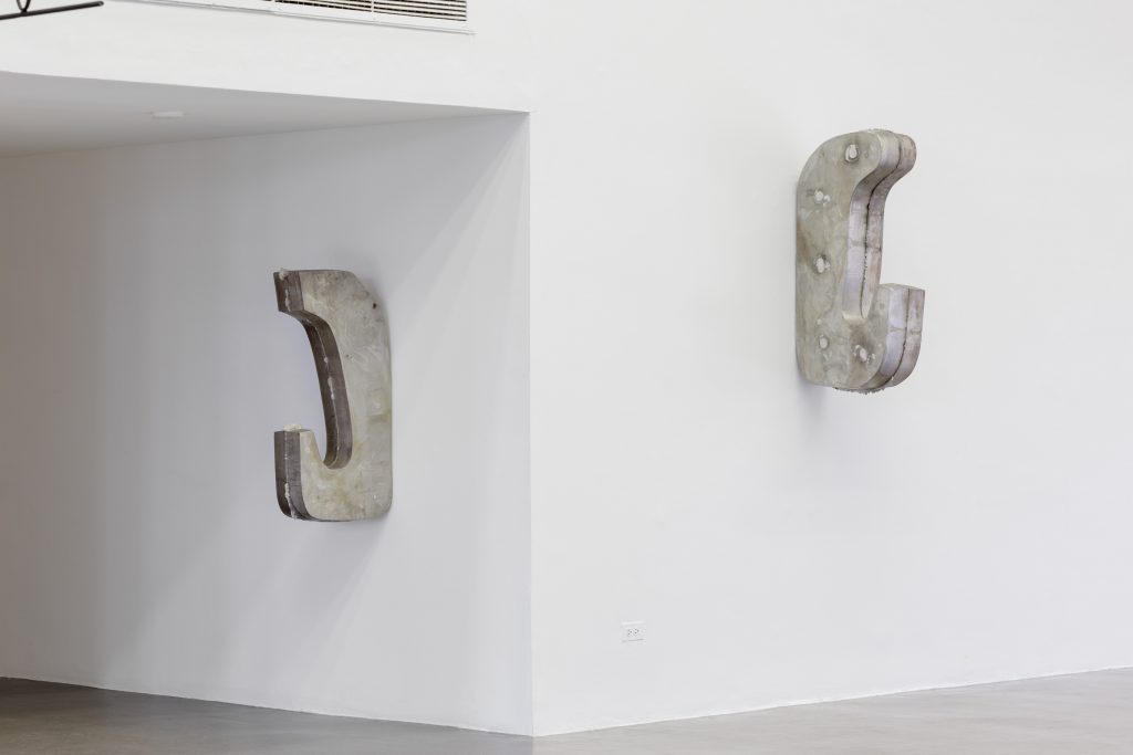Image: Two C-shaped gray sculptures are mounted on white walls. Nairy Baghramian, Mooring (Hanging), 2016 and Mooring (Hanging), 2016.  Photo: Useful Art Service