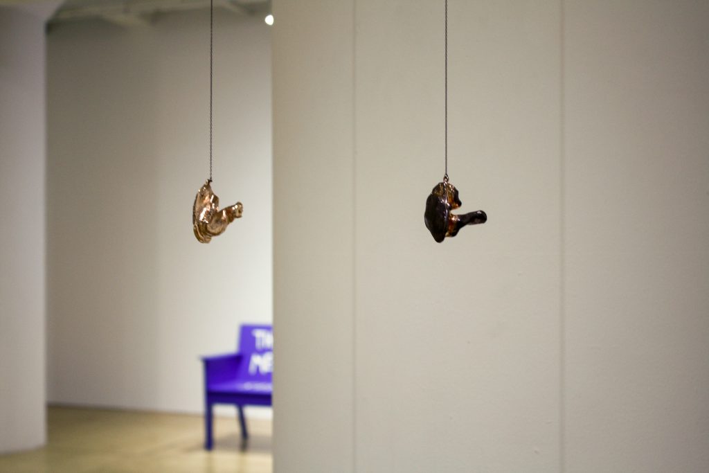 Image: Alison O'Daniel, The Audiologist's Poem (Barbara and Nadia), 2018, copper-plated medical silicone, chain. Two small metallic sculptures that are approximately 1.5 x 1.5 x 1 each hang from small chains in a gallery. Courtesy of the artist and Commonwealth and Council, Los Angeles.