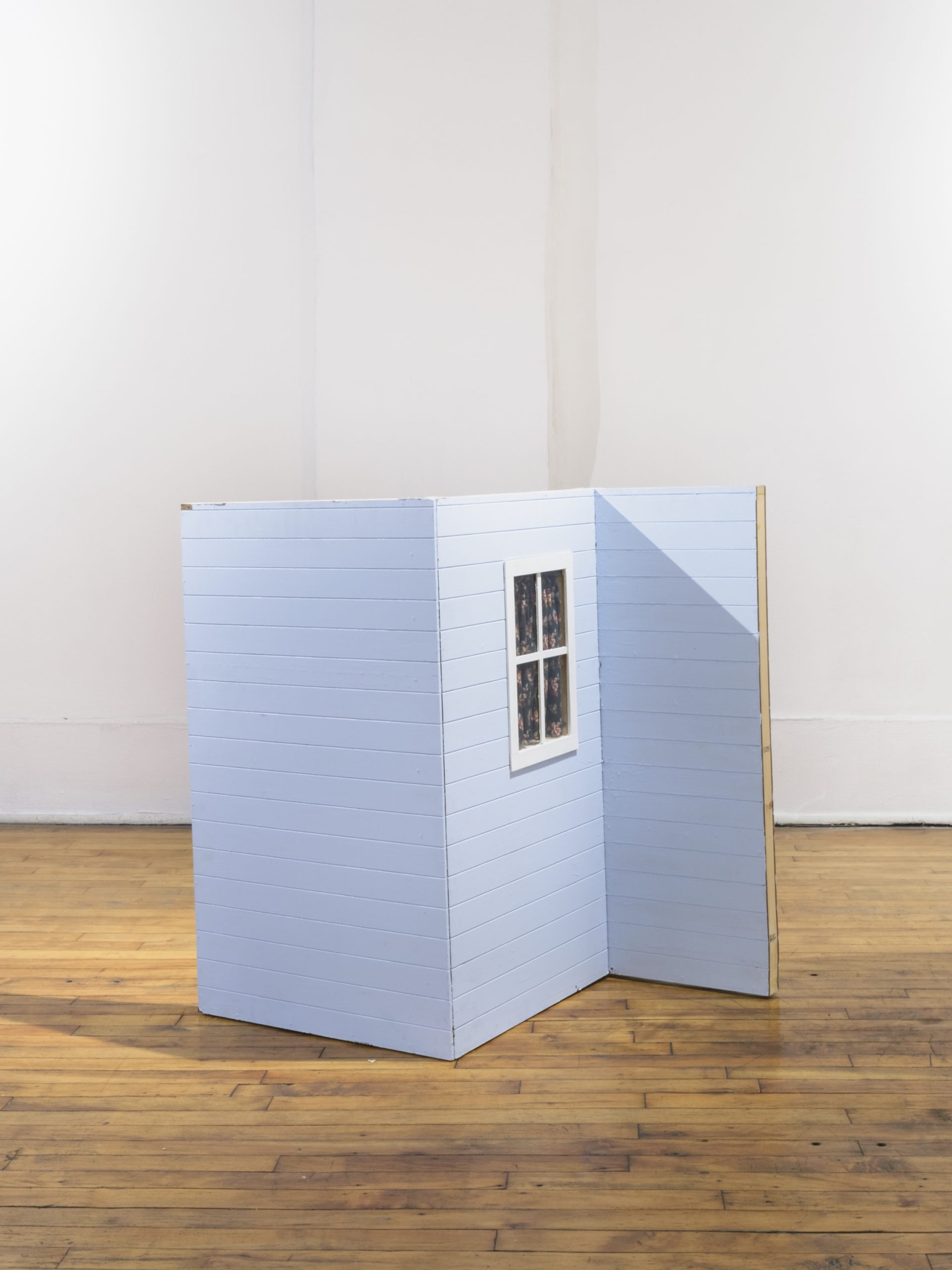 Image: Catherine Hu, Double-sided Outside, 2020, painted MDF, print- transfer on pine, floral fabric, 32" x 36" x 30". A partition-like structure that looks like the side of a light blue house with a window. Image courtesy of Heaven Gallery.