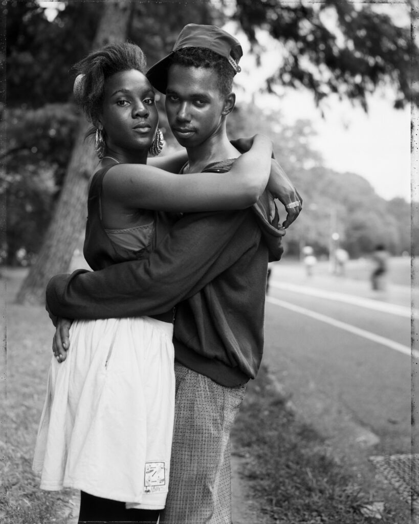 Image: Couple in Prospect Park, 1990 (printed 2018). Gelatin silver print, 21 7/8 x 17 1/2 inches. Grand Rapids Art Museum, Museum Purchase, 2018.22. © Dawoud Bey. Courtesy of Stephen Daiter Gallery. The image shows a Black man and woman embracing while looking straight at the viewer.