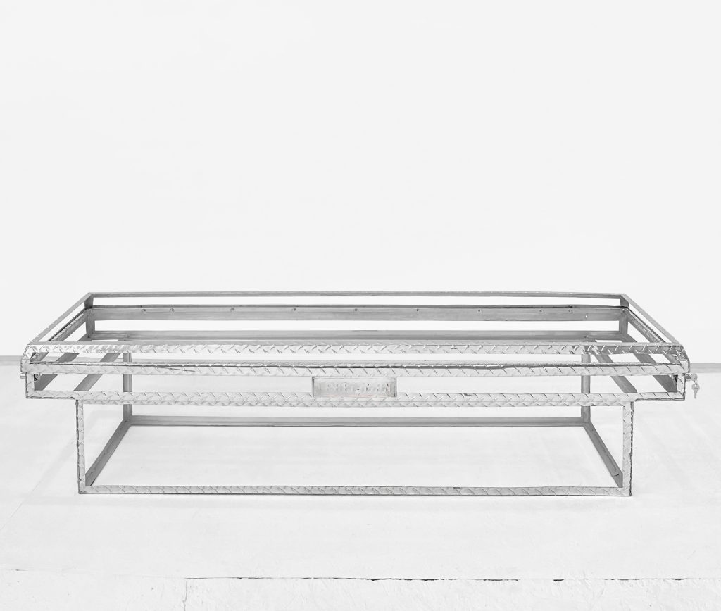 Image: Gary LaPointe Jr., ( crossover toolbox ), 2022, altered Craftsman aluminum crossover truck bed toolbox, keys, hardware, 71.36 x 19.57 x 17.21”. A completely see-through toolbox sits on a white floor. The edges of the toolbox are metal. Image courtesy of Roman Susan.
