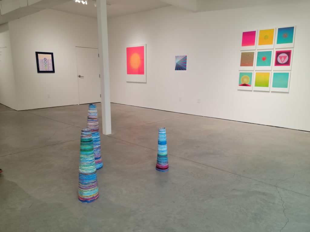 Image: Installation view of “Not a Certainty But a Circumstance” at Quappi Projects in Louisville, KY. Several brightly colored abstract pieces hang on the wall and sit on the floor of the gallery.