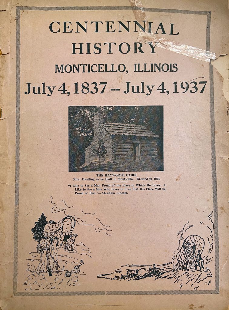 Image: The cover of the “Centennial History Monticello, Illinois July 4, 1837 – July 4 1937” booklet. The paper is yellowed and aged with the title in a large font. There is a photo of the Hayworth Cabin with a caption that the 1822 structure was the first dwelling to be built in Monticello, followed by an Abraham Lincoln quote. Photo by Jessica Hammie. 