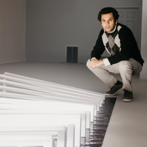 Featured Image: Amay Kataria pictured crouching next to his new work Supersynthesis at Mu Gallery Chicago.