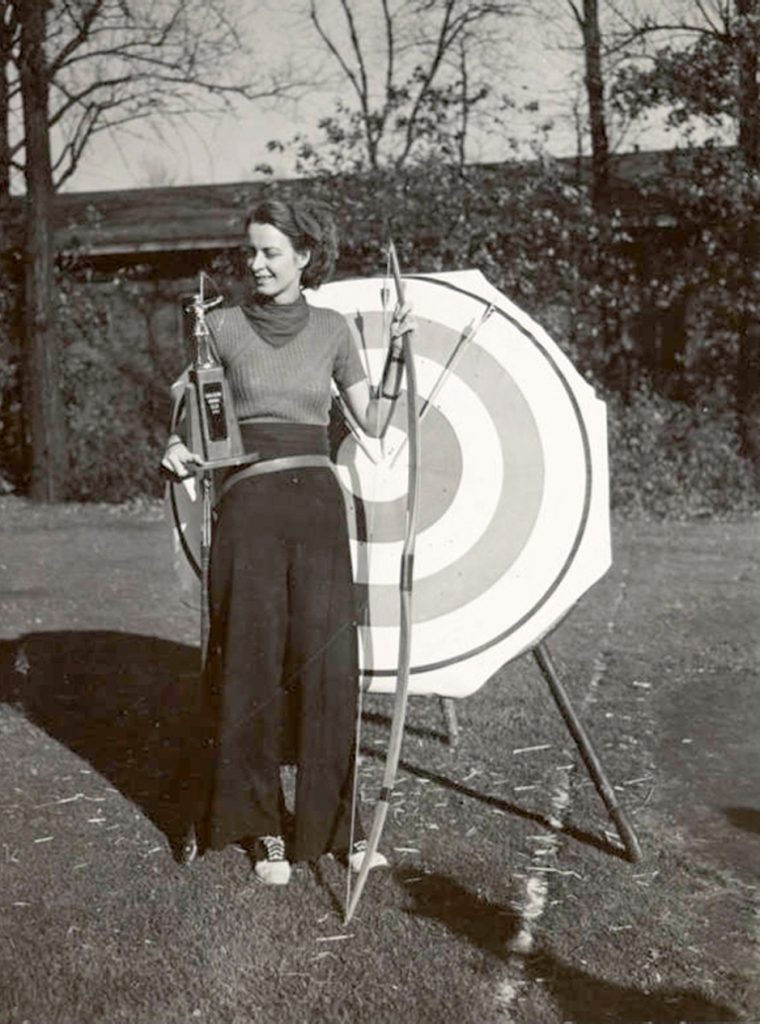 Image: Chicago Archery Club, ca. 1938. A black and white photograph of a woman holding a bow and arrow standing in front of a bullseye. Courtesy of the Washington Park Camera Club.