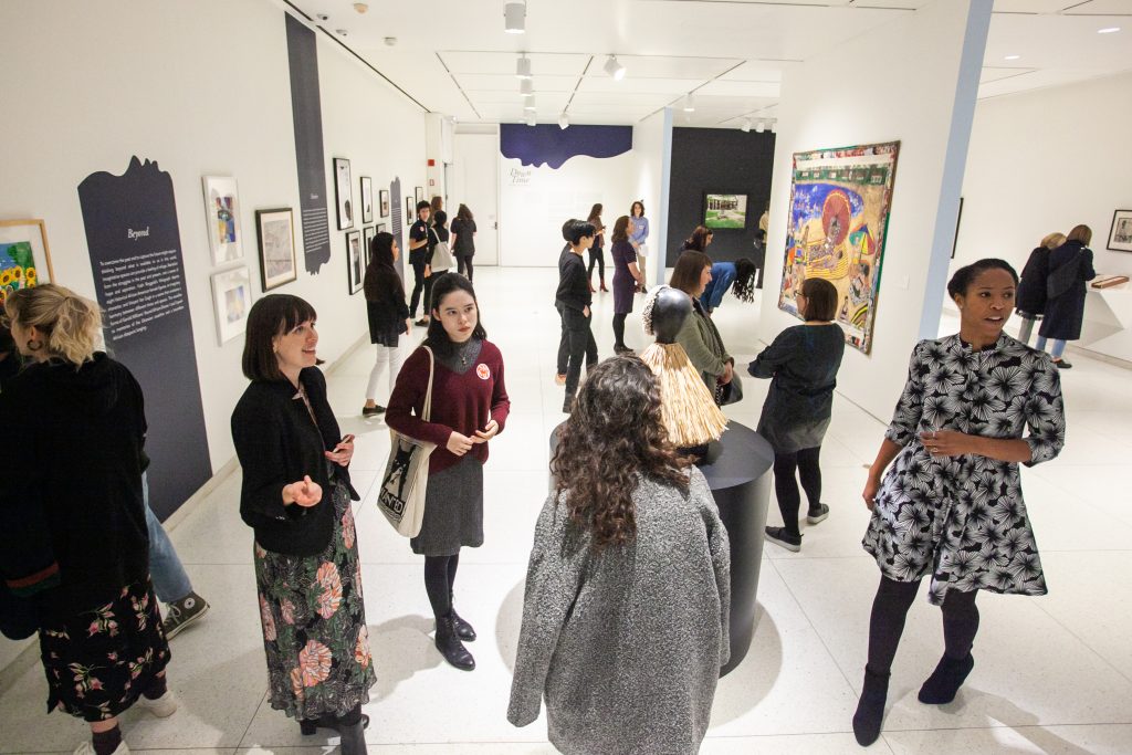Image: A medium-sized group of people in a gallery casually observing the art. Opening reception of the student-curated exhibition "Down Time: On the Art of Retreat," at the Smart Museum of Art at the University of Chicago on Thursday, October 24, 2019. Photography by Eddie Quinones.
